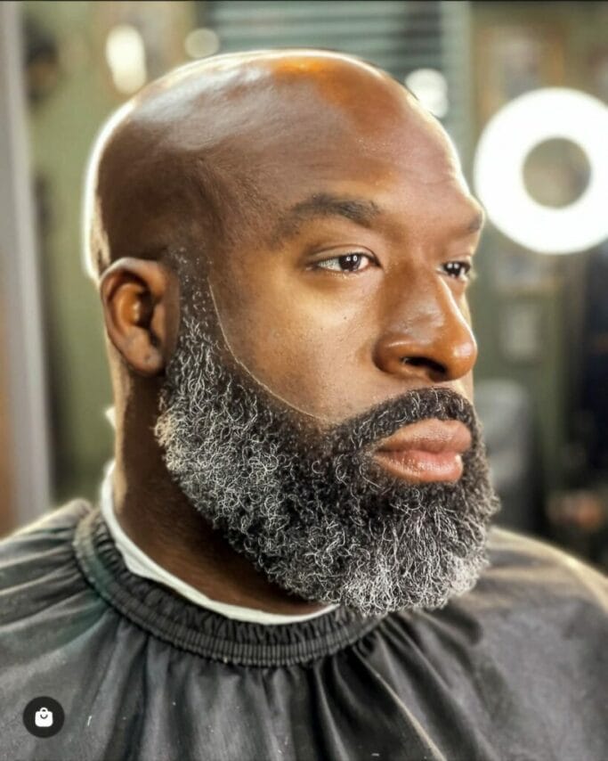 A bald haircut with full beard